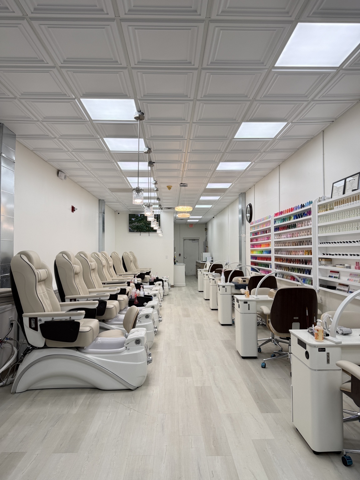 EnVy Nails salon interior with cream pedicure chairs, manicure stations, and colorful polish displays